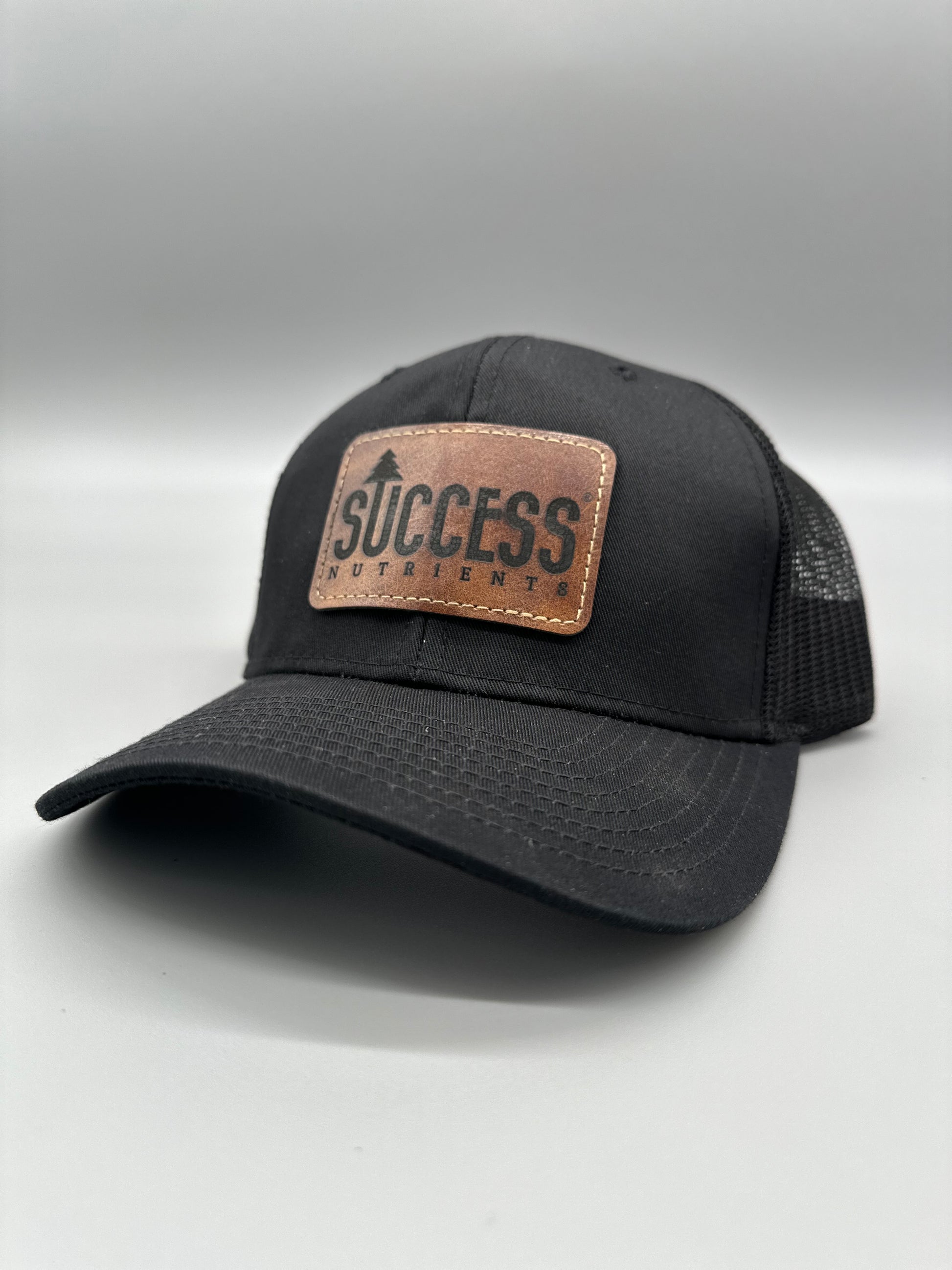 Black trucker hat with the Success Nutrients logo on a brown leather patch